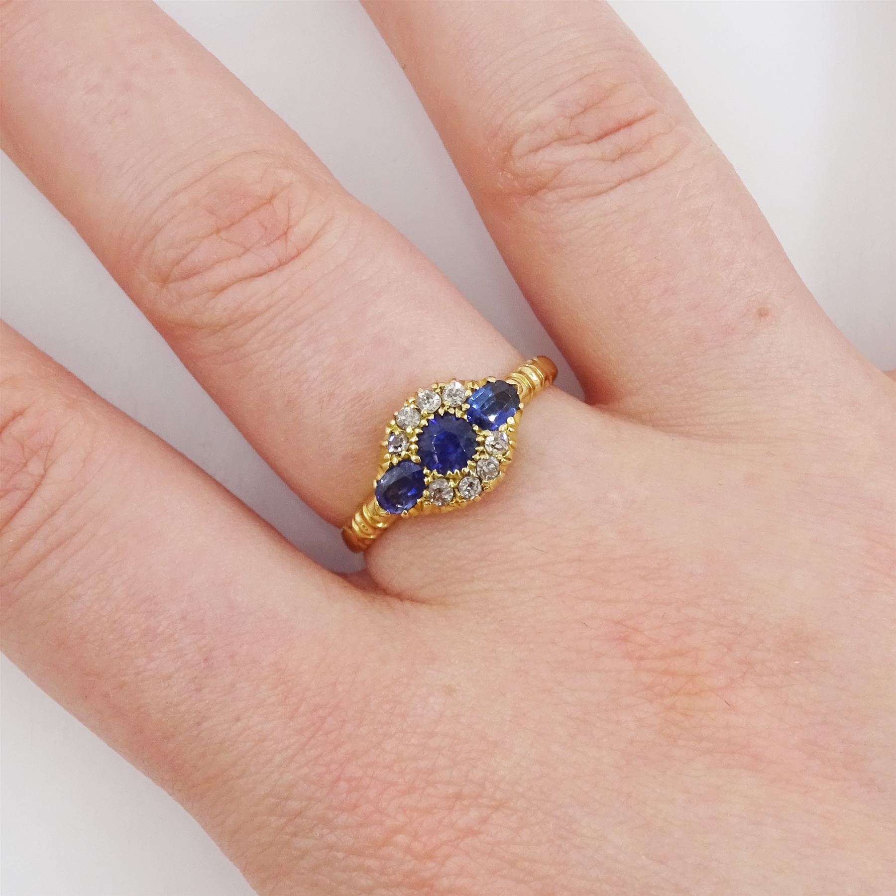 Early 20th century 18ct gold three stone oval cut sapphire and eight stone diamond cluster ring, Chester 1916