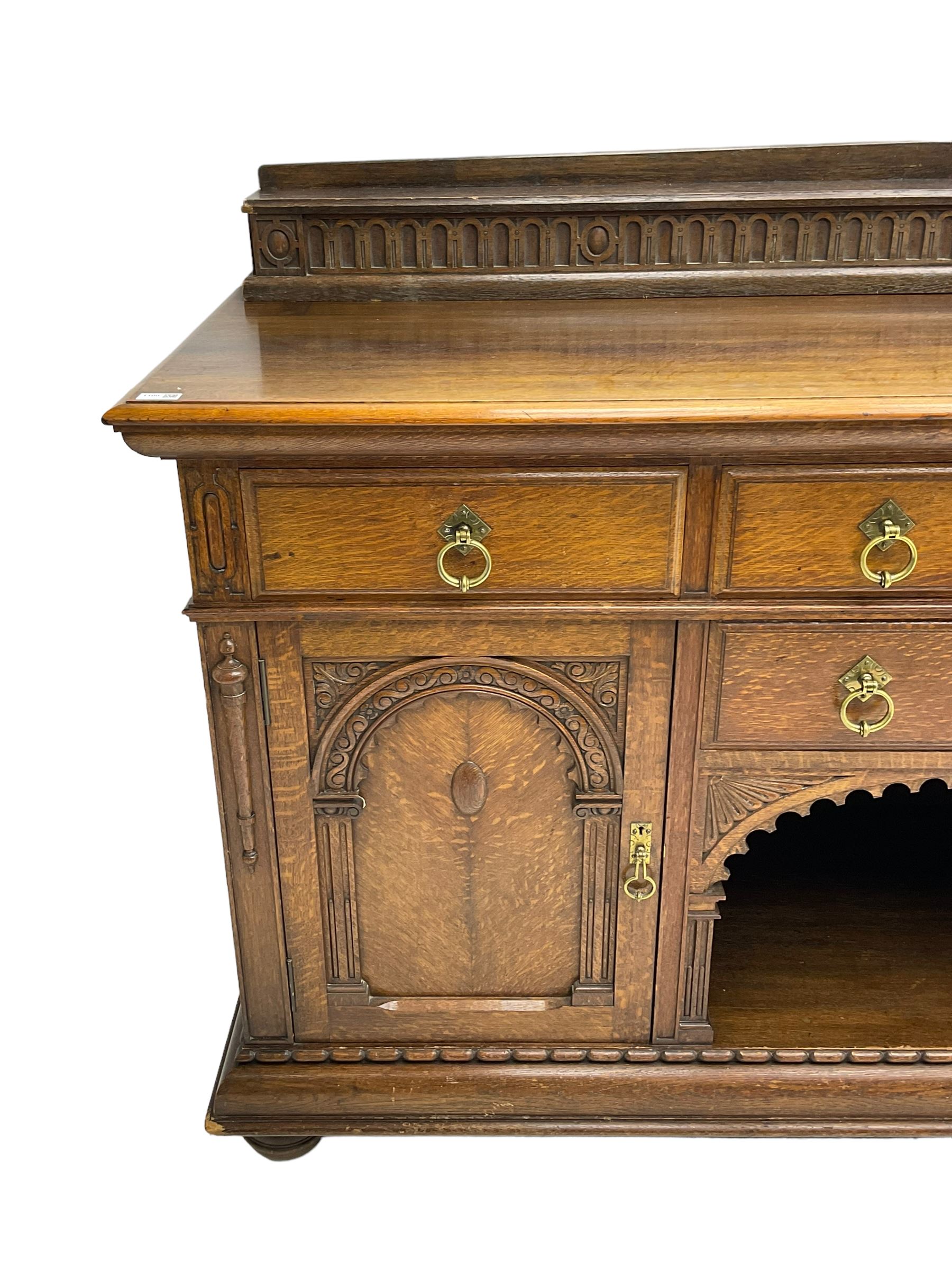 Edwardian oak sideboard, raised arcade carved back over rectangular top, fitted with four drawers, two arch carved doors doors flanking open arched centre, on turned feet