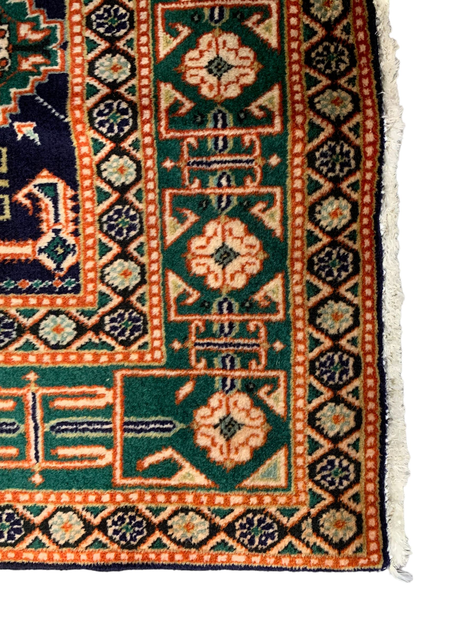 Small Persian indigo ground rug, the field decorated with Gilt motifs with trailing bead and stylised foliage, emerald green ground border decorated with geometric design and flower heads