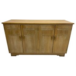 Early to mid-20th century limed oak sideboard, four doors carved with arcades enclosing shelves and two drawers, on bracket feet