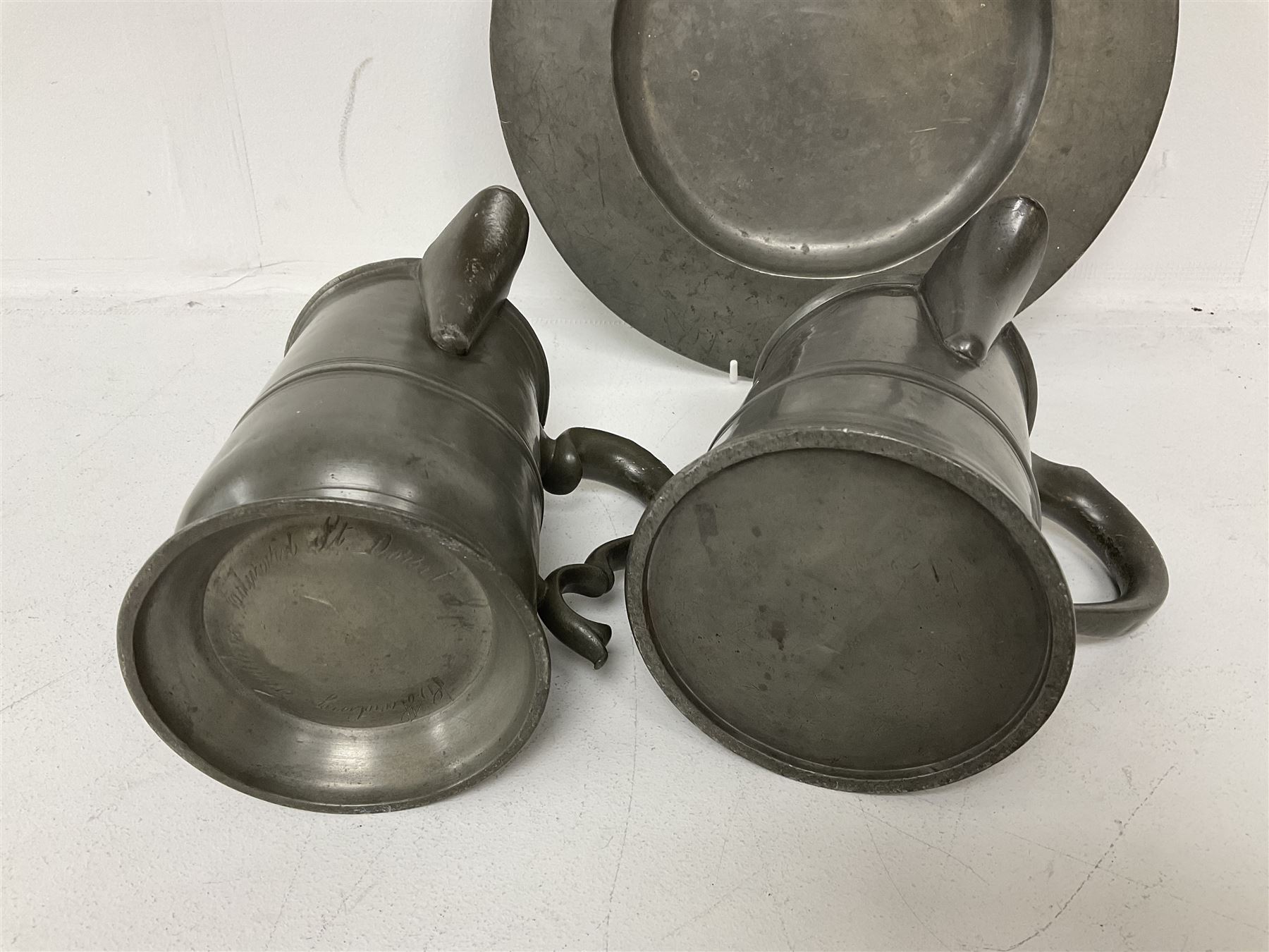 18th century pewter plate, with stamped London Superfine and crowned rose mark verso, together with two 19th century pewter side pouring tavern quart mugs, each indistinctly engraved (one 'R Harding Feathers')