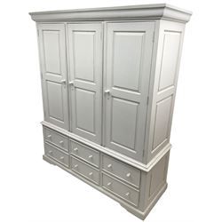 White painted triple wardrobe, projecting moulded cornice over three panelled doors, the interior fitted with hanging rails, four drawers and hinged cupboard to base, on bracket feet