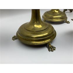 Pair of brass candlesticks, raised upon three lion paw feet, together with fire dogs with lion masks to the front and fire tools 