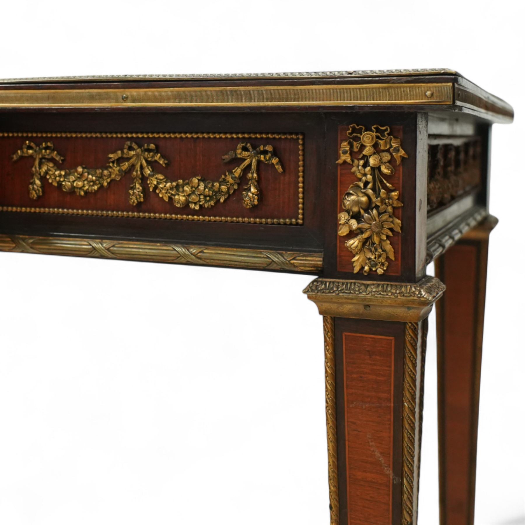 Fine 19th-century Louis XVI-style mahogany and gilt bronze-mounted writing table, rectangular top with a gilt tooled tan leather writing surface within a moulded gilt bronze edge above a frieze fitted with three drawers, mounted with floral and foliate gilt bronze swags  and borders, raised on square tapering legs with acanthus mounts and toupie feet