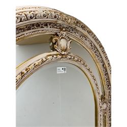 Large painted and gilt arched wall mirror, the frame decorated with scrolling leafy branches, central bevelled mirror mirror surrounded by plain panels, decorated with cartouche mounts 