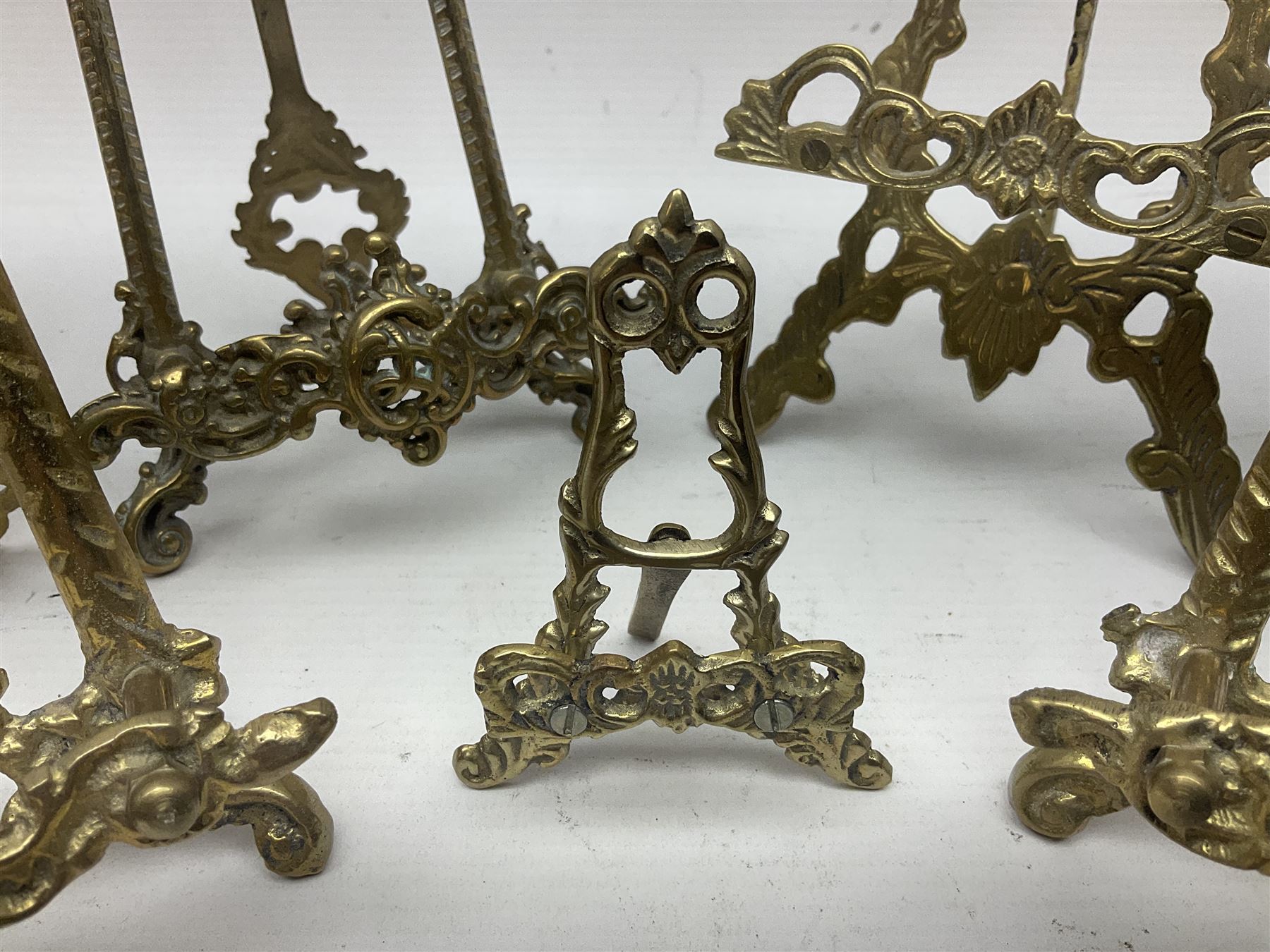 Nine ornate cast brass easel stands of various sizes, H24cm