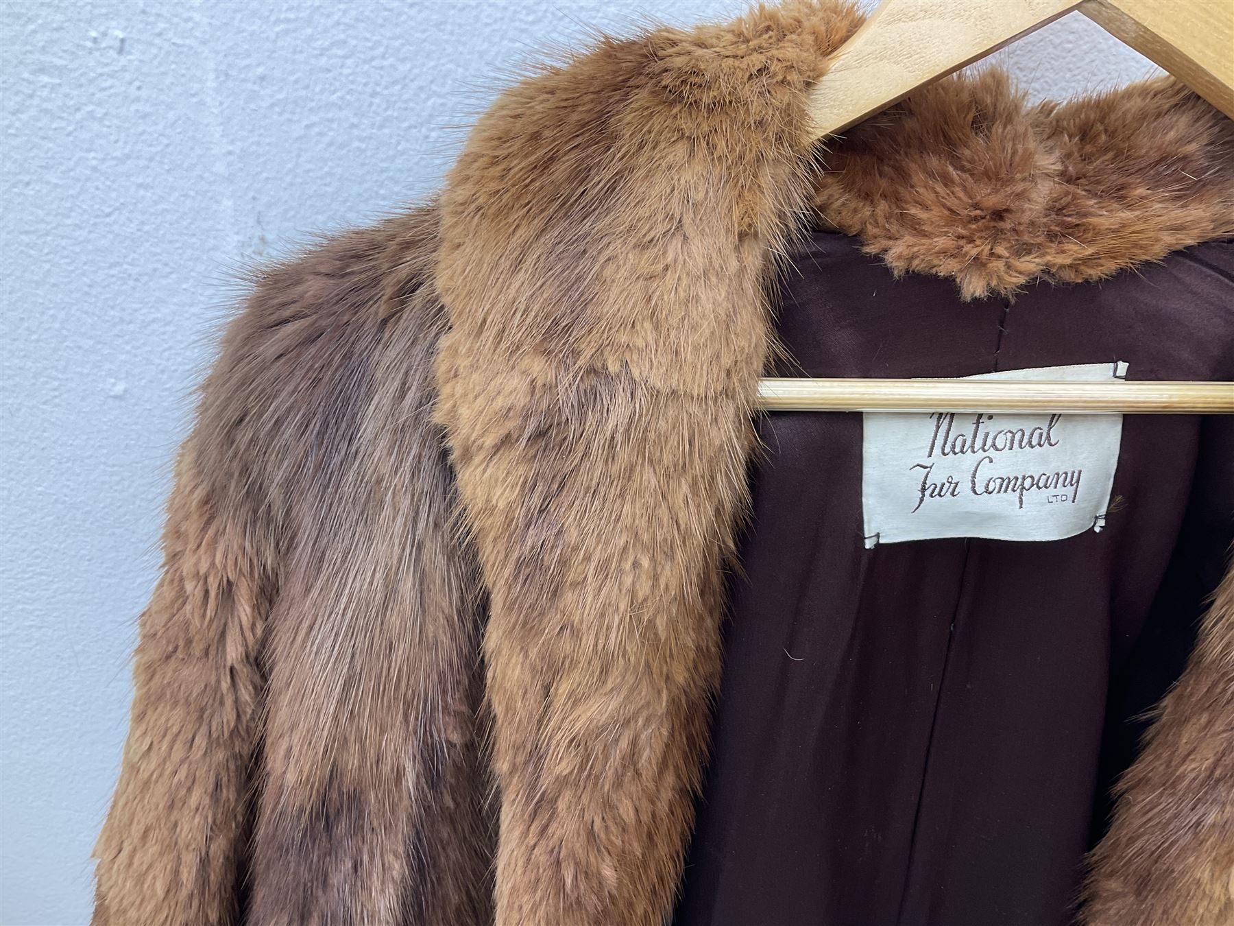 Brown mid length musquash fur coat by National Fur Company together with white rabbit cape