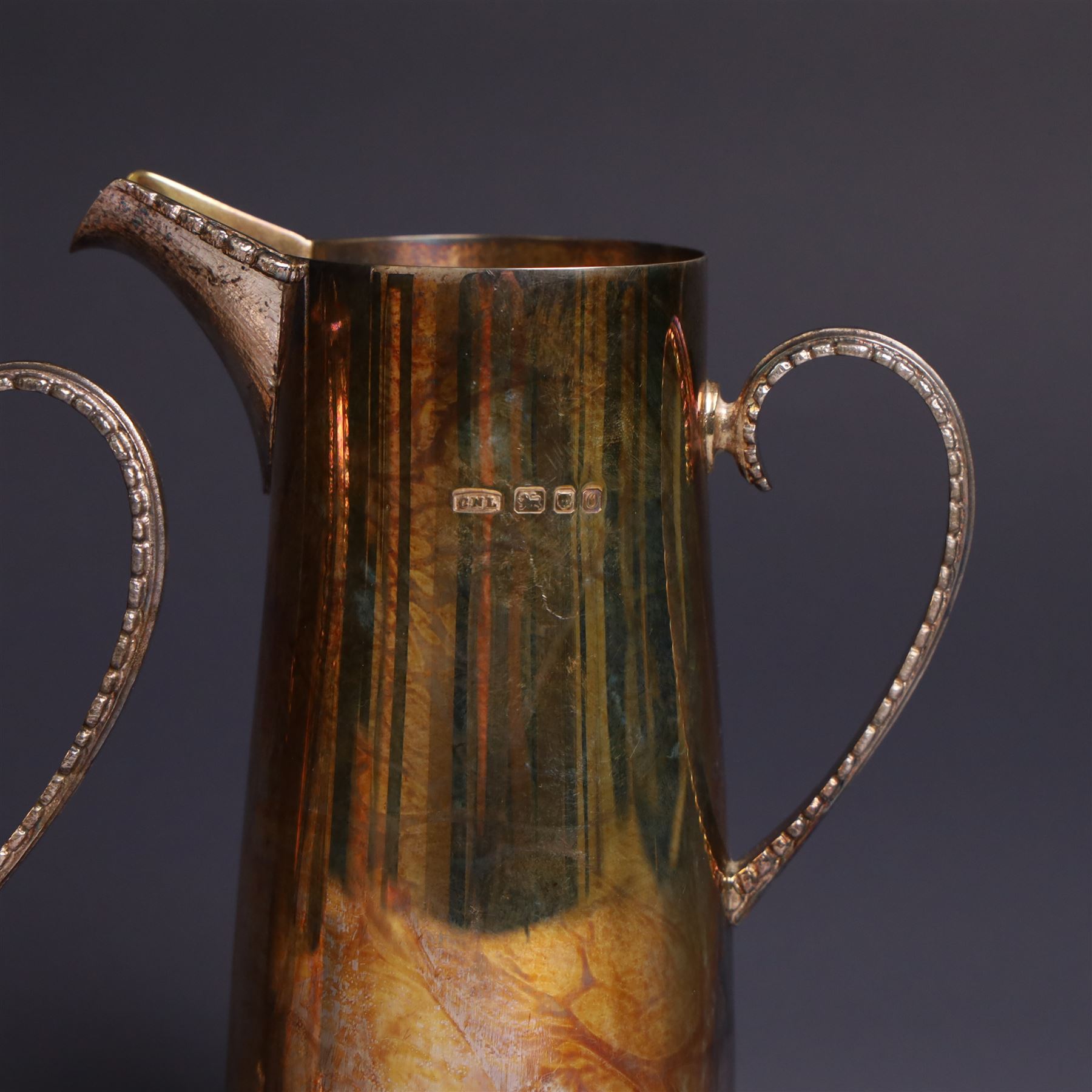 Two graduating silver milk jugs, each of tapering cylindrical form, with engraved central cartouche to body and upon three paw feet, hallmarked Christopher Nigel Lawrence, London 1988, tallest H13cm