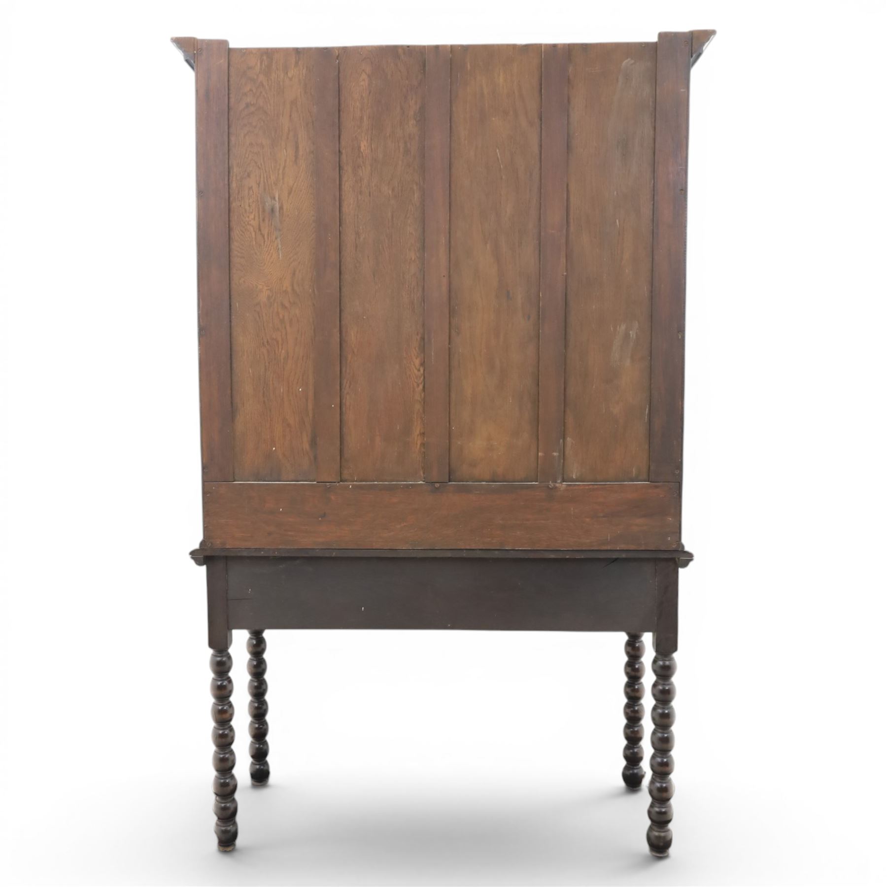 Early 20th century Jacobean Revival dark stained oak dresser, the associated upper section enclosed by twin glazed doors with shaped moulded glazing bars, over separate base fitted with two drawers, raised on bobbin turned legs