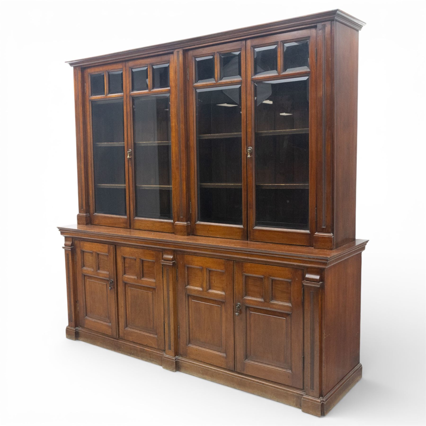 Late 19th century walnut library bookcase, fitted with four display doors with astragal bevelled panes, raised upon a four cupboard base with fielded panel doors