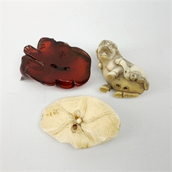 Japanese Meiji ivory Netsuke, modelled as a frog upon a lily pad, together with a further example modelled as a Dog of Fo, and a simulated amber netsuke modelled as a cat and kitten, (3)   