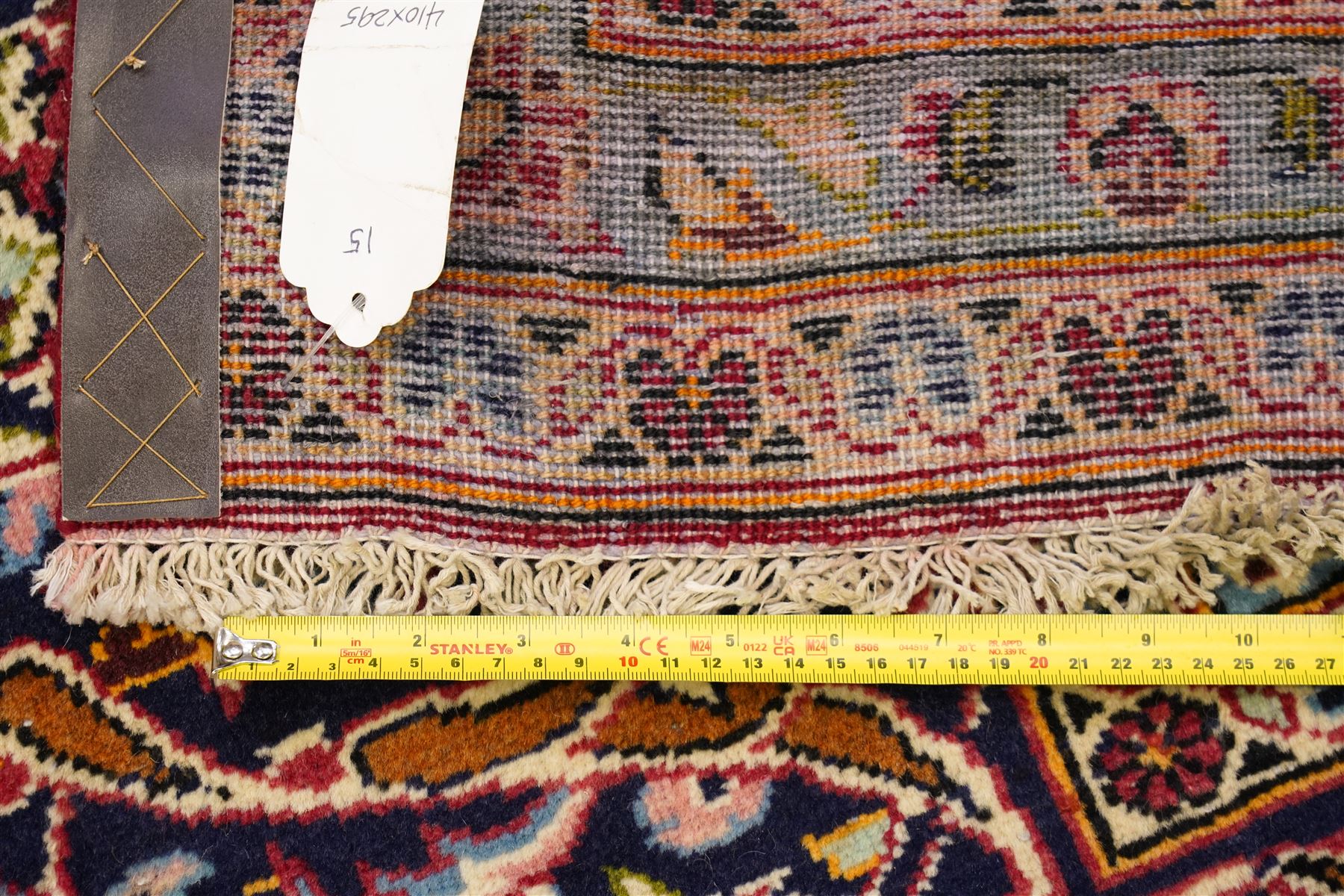 Persian Kashan hand-knotted carpet, madder red ground centred by shaped dark navy and ivory floral medallion with pendants, surrounded by scrolling vines, palmettes and flowerheads, dark navy spandrels, enclosed by dark navy floral border with multiple narrow floral guard stripes