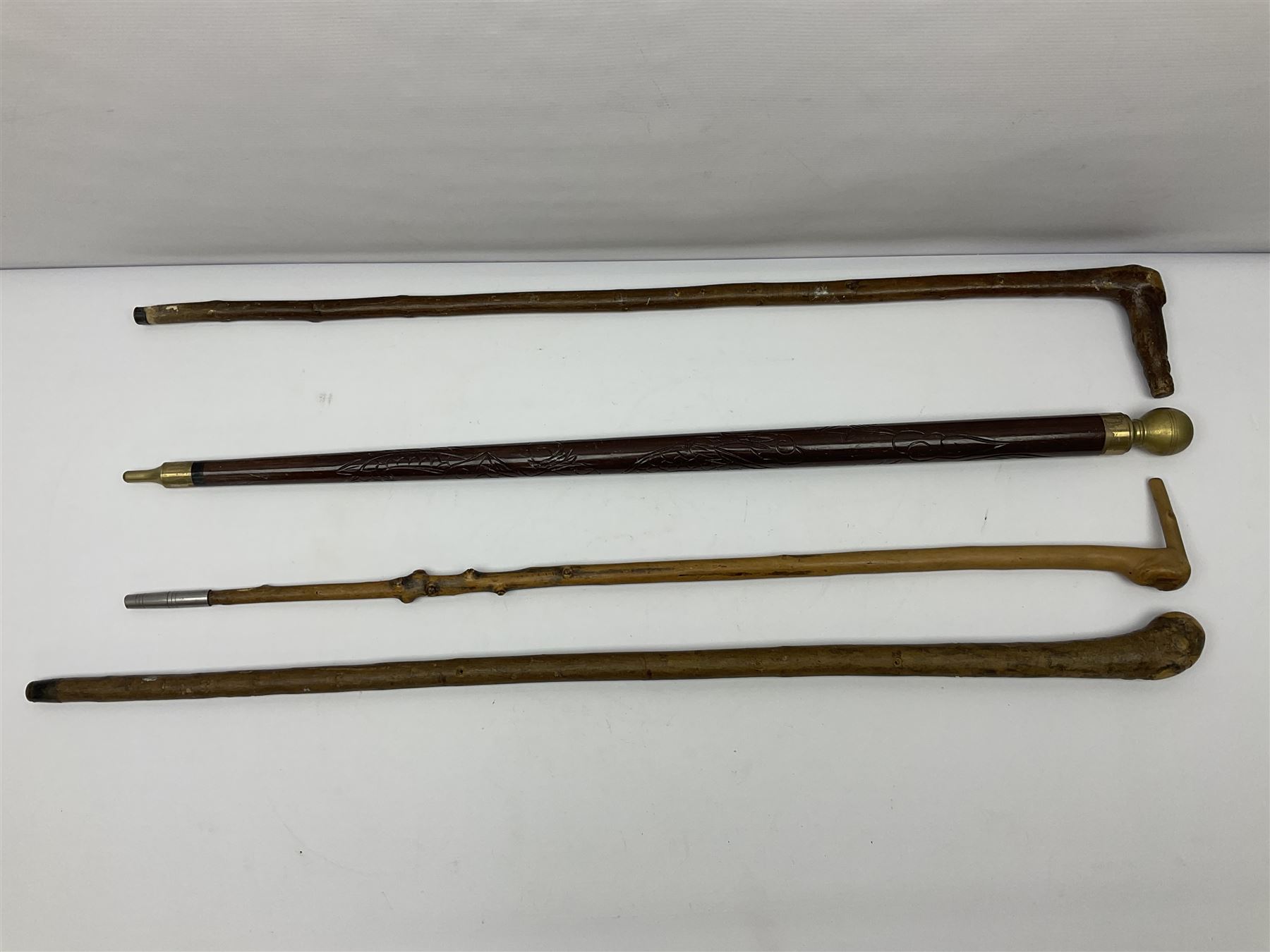 Four wooden walking canes, including a carved mahogany snooker cue example, tallest H86cm