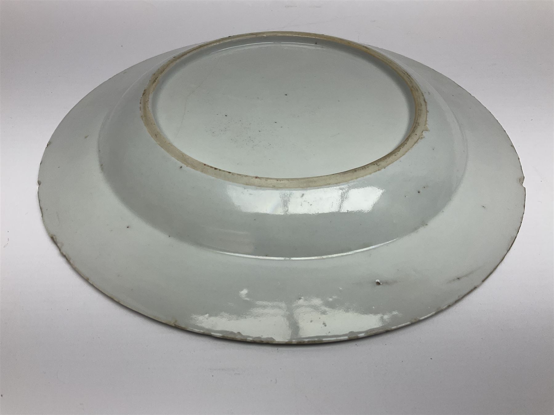 Three 18th century Chinese Famille Rose plates, the first example enamelled with blossoming peonies, rockwork and fence, the other two examples of similar design, decorated with blossoming peonies and sprigs within shaped inner borders, each approximately D23cm