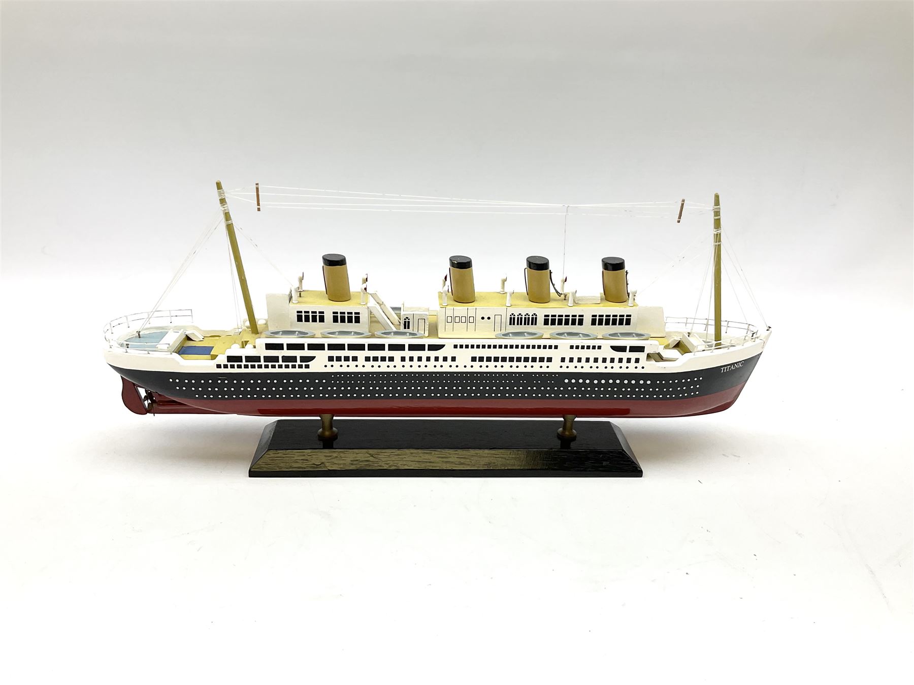 Wooden model of RMS Titanic, on a fixed black stand bearing plaque inscribed 'Titanic 1912', L54cm, H22cm, together with model of a sloop, gaff rigged on stand bearing plaque inscribed 'Sloop' L32cm, H42cm; and model of a fishing trawler on a stand bearing plaque inscribed 'Chalutier' L35cm, H28cm (3)