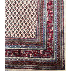 Northwestern Persian Bottehmir hand-knotted rug, ivory field with an all-over design of boteh motifs arranged in diagonal rows within multiple borders and a primary madder red field with stylized vine and flowerhead motifs, 320cm x 214cm 