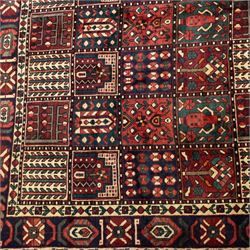 Bakhtiari wool rug, compartmented garden design field with panels of stylised trees, flowers and geometric motifs, enclosed by dark blue main border with repeating floral medallions and guard stripes