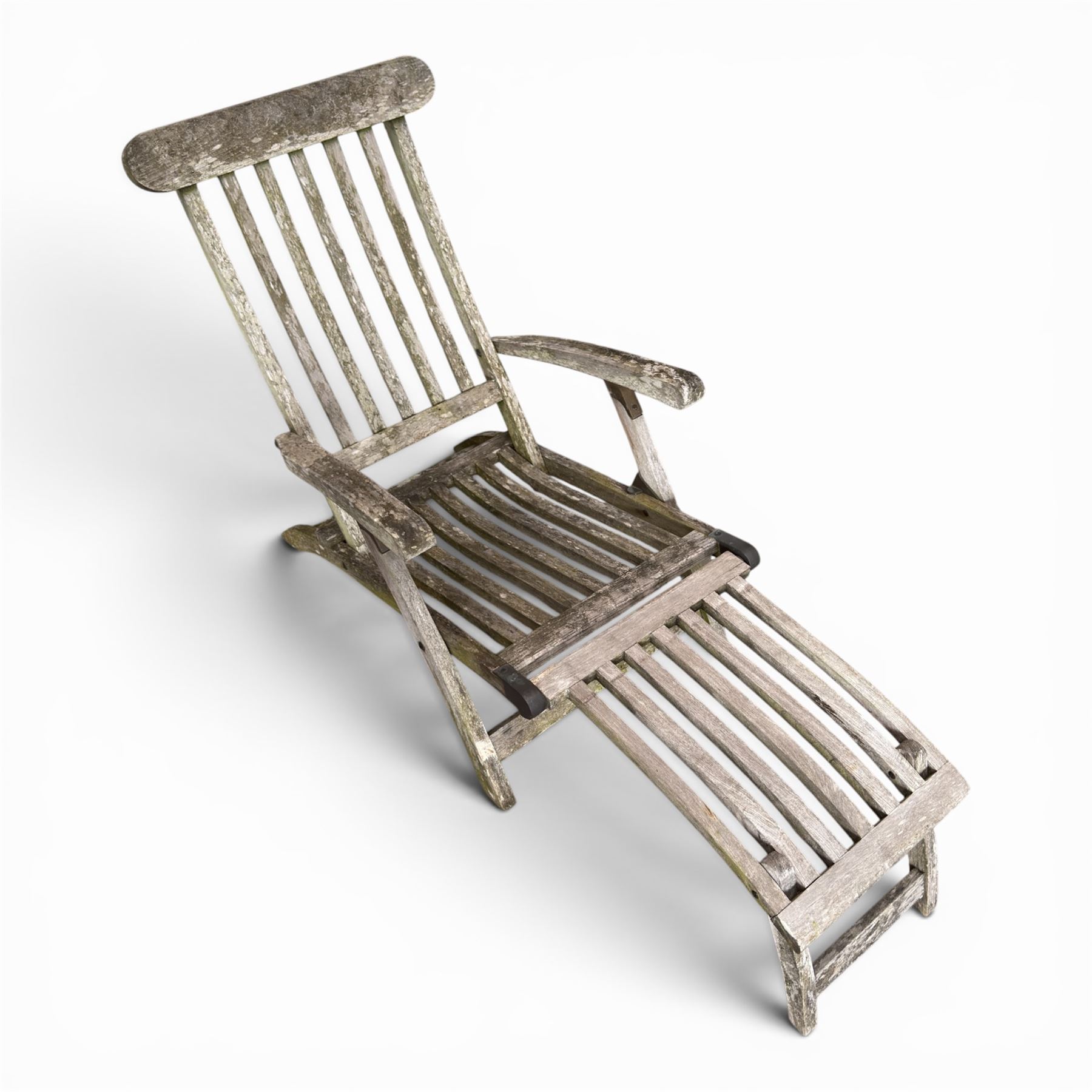 Pair of teak reclining garden steamer armchairs, each with an adjustable slatted back, curved slatted seat and footstool