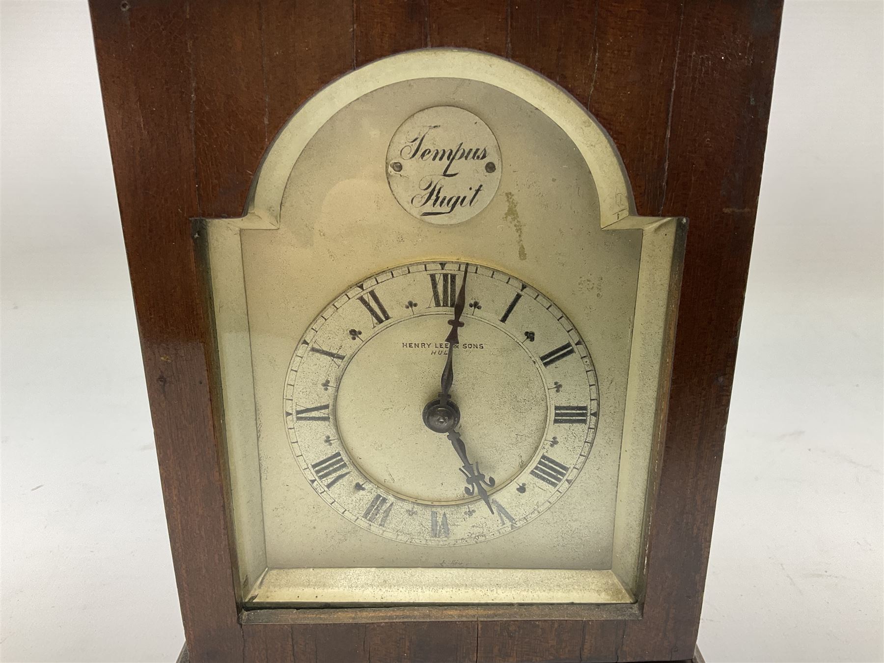 Georgian style mahogany cased bracket type clock retailed by Henry Lee & Sons Hull, with brass carrying handle to the pagoda top, arched silvered dial with Tempus Fugit plaque, raised chapter ring with Roman numerals enclosing French brass eight day movement with integral key, on bun feet, H24cm  