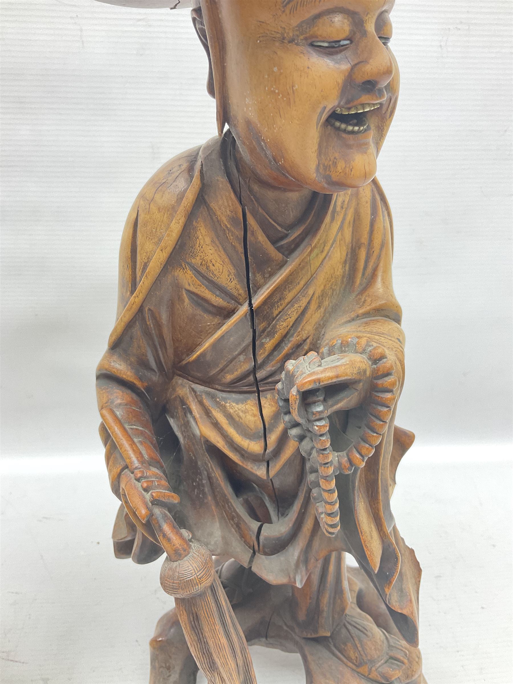 Pair of Japanese carved wooden figures, modelled as merchants in traditional dress, upon pierced naturalistic bases, tallest H39cm