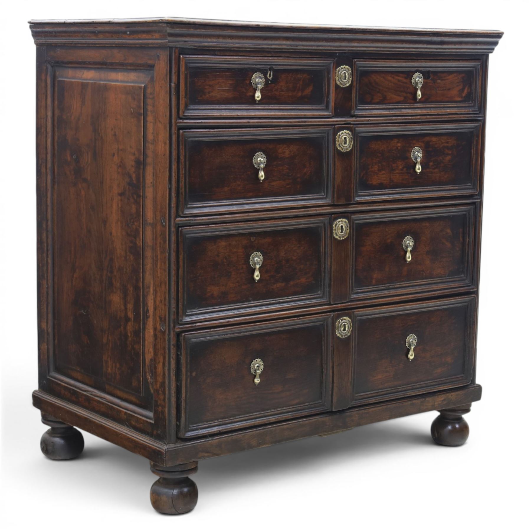 Late 17th century moulded front oak chest of drawers, rectangular plank top. above two banks of four graduated drawers, central escutcheons and drop handles, on squat bun feet