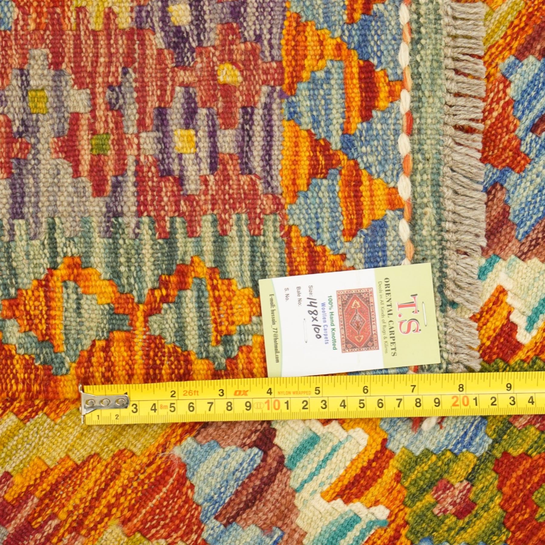 Afghan Chobi flatweave kilim, with a repeating stepped diamond medallion design in ivory, green, rust, teal, purple, indigo, and framed by chevron and geometric borders