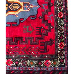 Northwestern Persian Cirjan hand-knotted carpet, madder red field with three linked stepped lozenge medallions in blue, ivory and green, flanked by angular motifs within a dark green border of serrated leaves and rosettes 