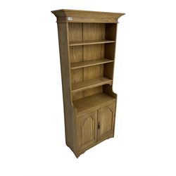 Light oak open bookcase cupboard, projecting cornice over three shelves, fitted with double cupboard enclosed by arched panelled doors 