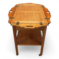 20th century mahogany butler’s tray on stand, with folding gallery tray top featuring shaped hand grips and brass hinges, fitted with single drawer and lower shelf, on square section legs with pierced brackets and castors