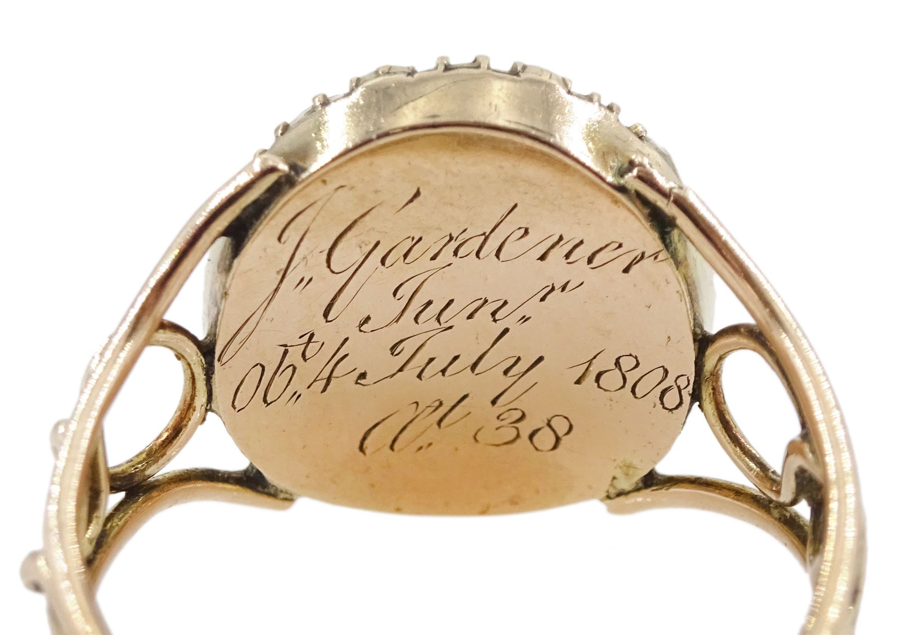 George III 9ct rose gold garnet and pearl mourning ring, single cabochon garnet, with split and seed pearl surround and pierced design shoulders, the back inscribed and dated 1808