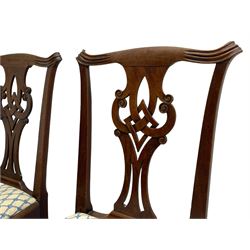 Set four late Georgian mahogany dining chairs, shaped cresting rail with carved ears over Chippendale style splat, pierced and carved with scrolls and interlocking lozenge, upholstered drop in seats, on square supports joined by plain stretchers