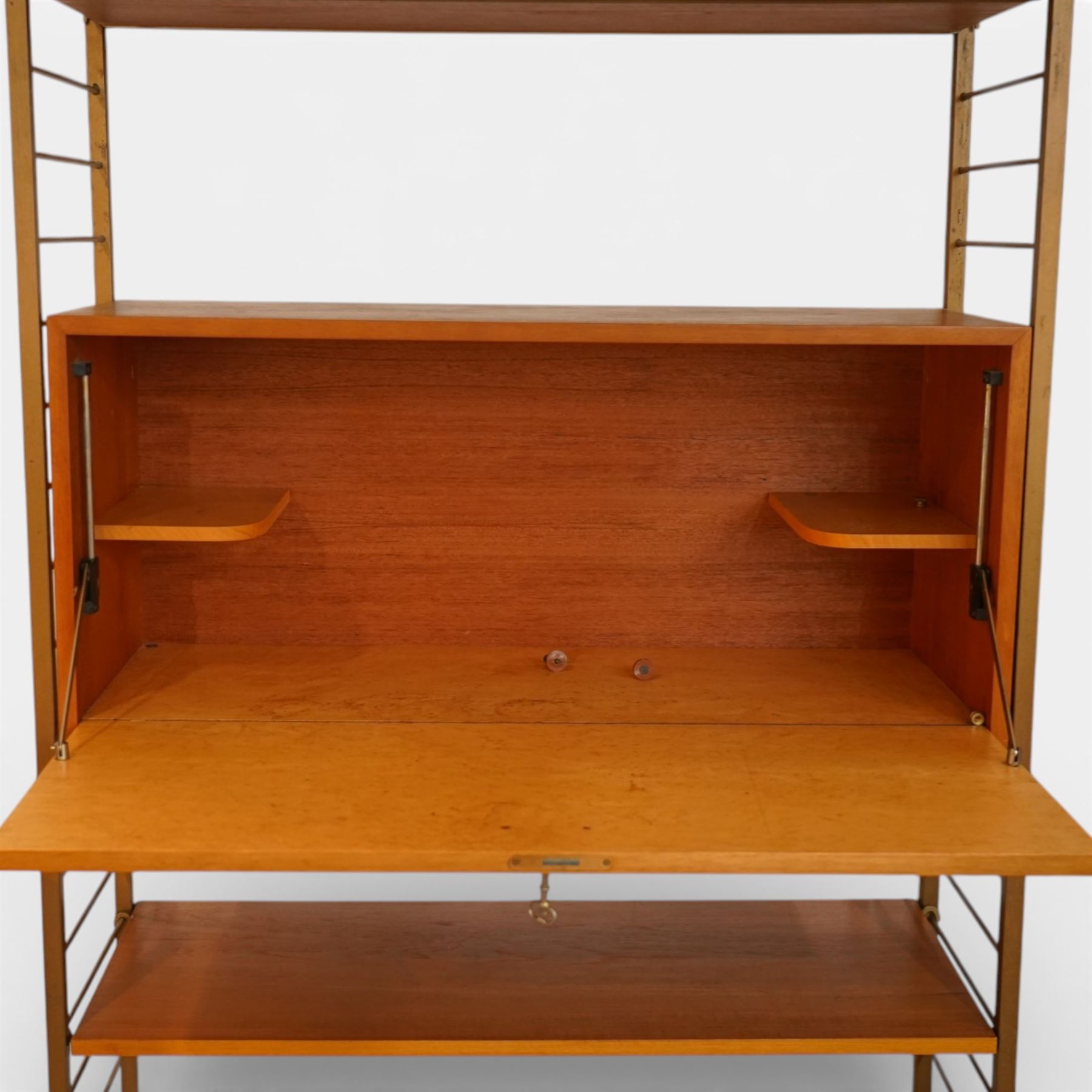 Staples - 'Ladderax' wall mounted modular teak unit, comprising two shelves, a fall front cabinet above three drawer unit below, supported on metal ladder frames 