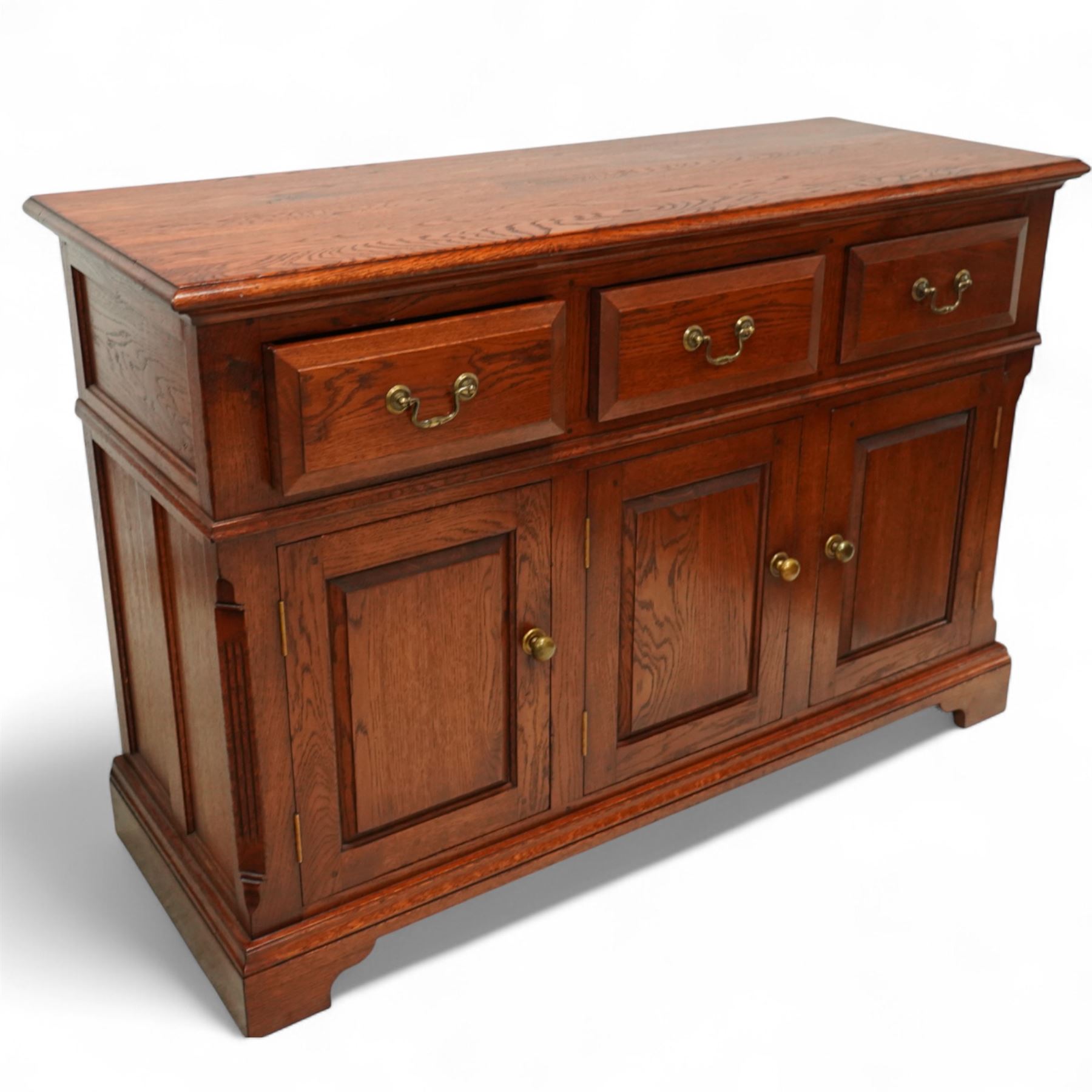 20th-century oak side cabinet, rectangular top above an arrangement of three drawers and three panelled cupboard doors, fitted with brass knobs, raised on bracket feet  