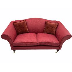 Traditional design two seat sofa, upholstered in red fabric, turned mahogany feet with brass castors