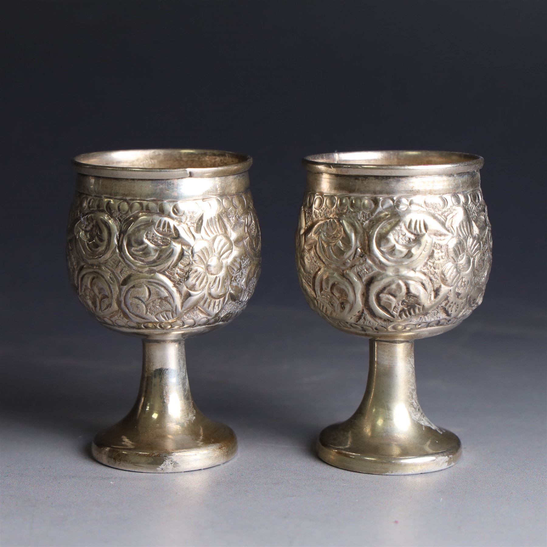 Pair of miniature Indian silver goblets, with embossed floral and foliate decoration, H6.5cm