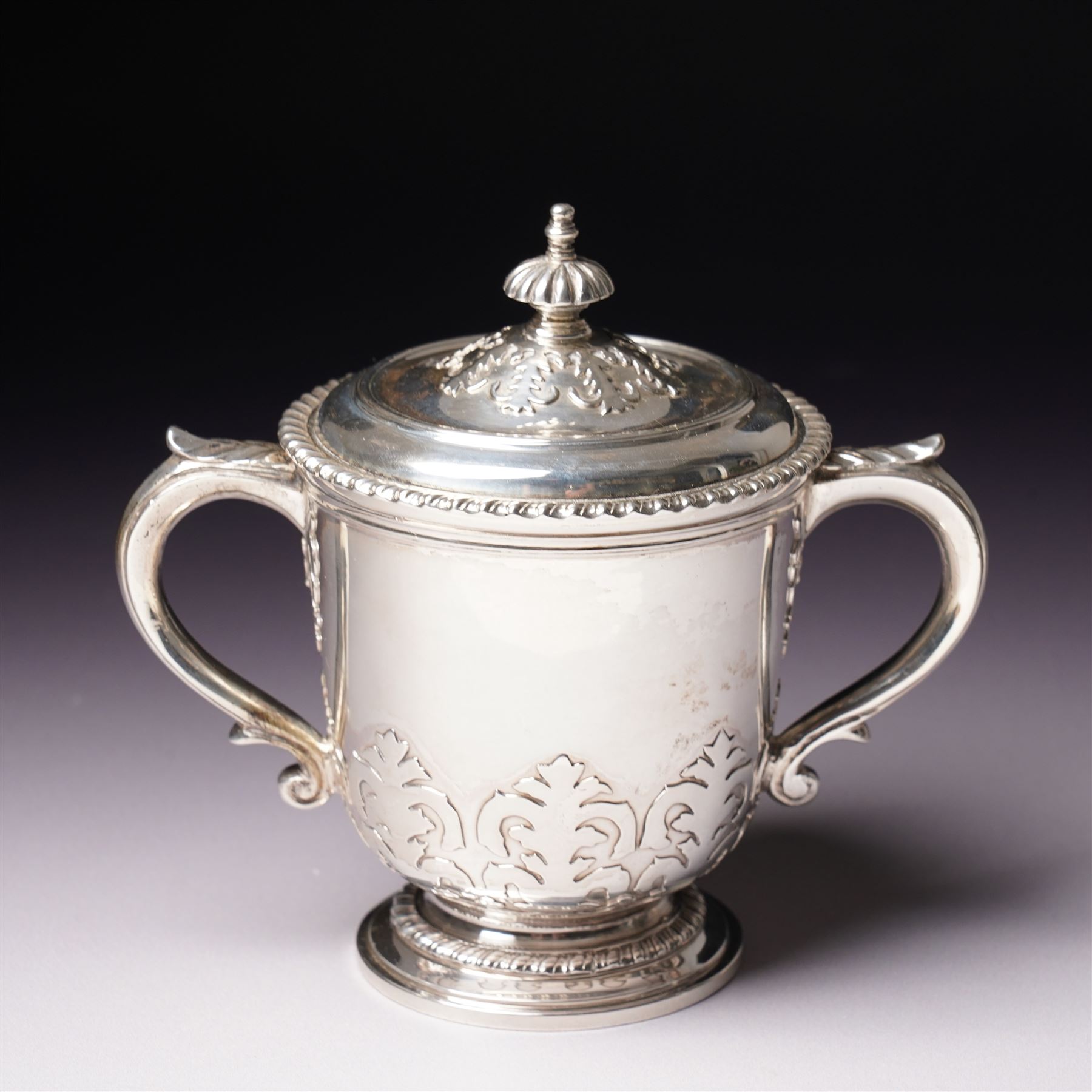 Silver two handled cup and cover with loop handles, raised stylised leaves and gadrooned edge H11cm London 1936 Maker Goldsmiths & Silversmiths Co. Ltd