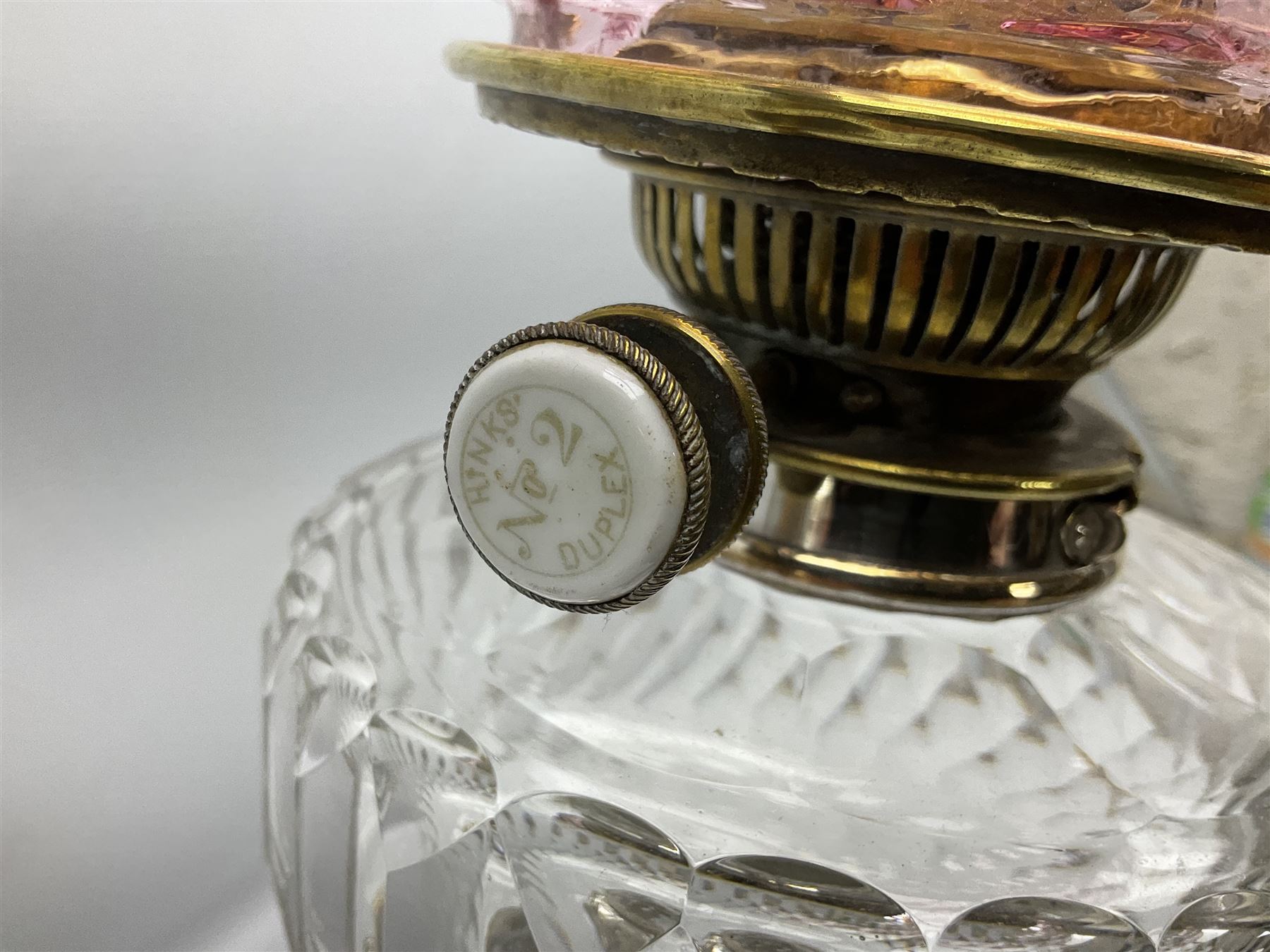 20th century Hawksworth, Eyre & Co silver plated oil lamp, the octagonal stepped base with engraved dedication, leading to an octagonal column supporting a faceted clear glass reservoir, Hinks Duplex burner, clear glass chimney, and cranberry glass shade, overall H71.5cm