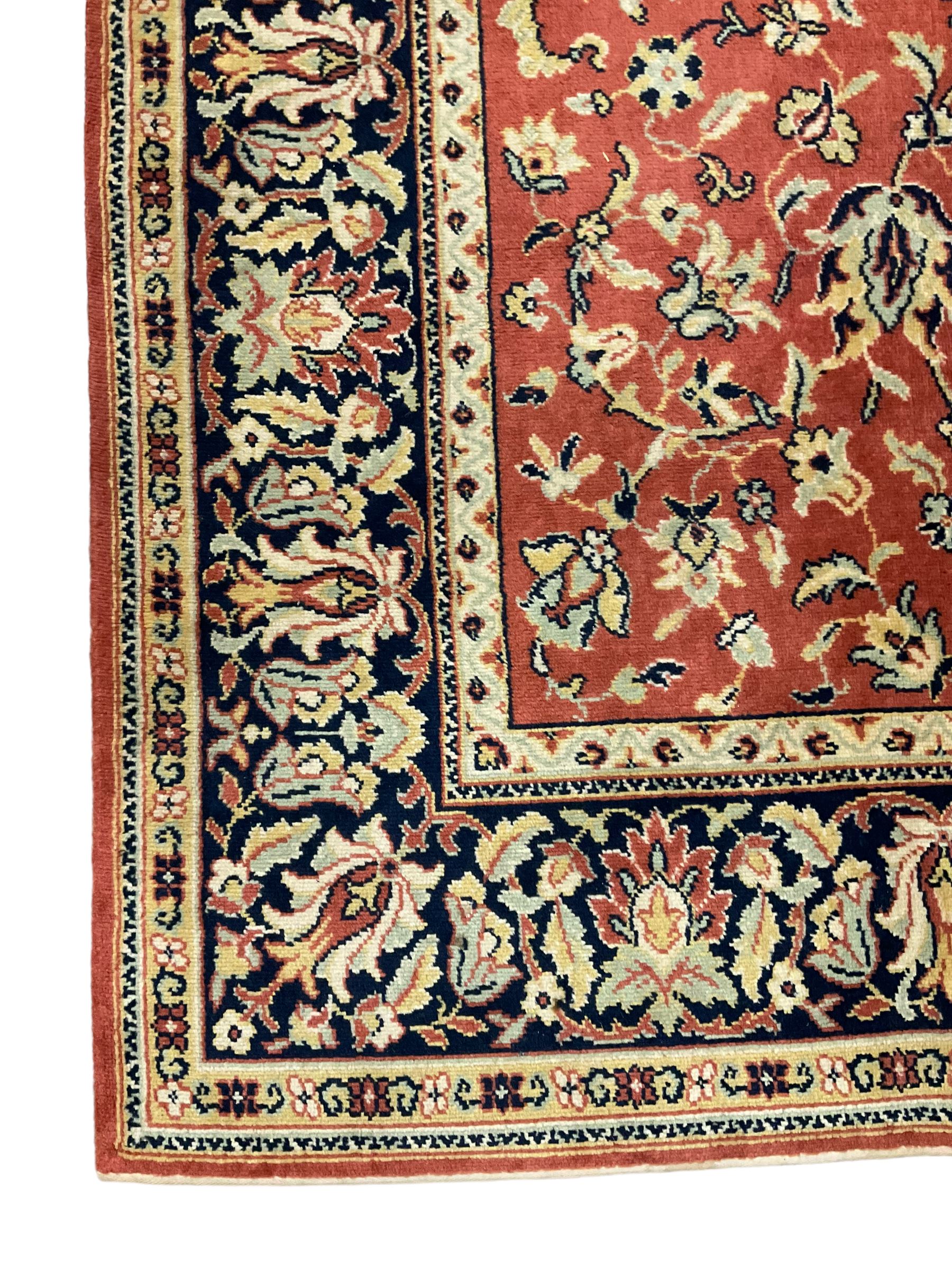 Large Persian design red ground rug, the field decorated with interlacing branches and stylised plant motifs, repeating border with further plant and floral motifs
