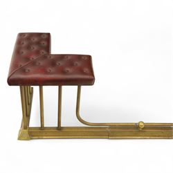 Late Victorian brass and cast iron club fender, burgundy leather buttoned seat pads, secured by bar uprights at the front and back, and a cross stretcher held in place by further bar uprights on a chamfered platform base, circa 1890, internal base dimensions 127cm 