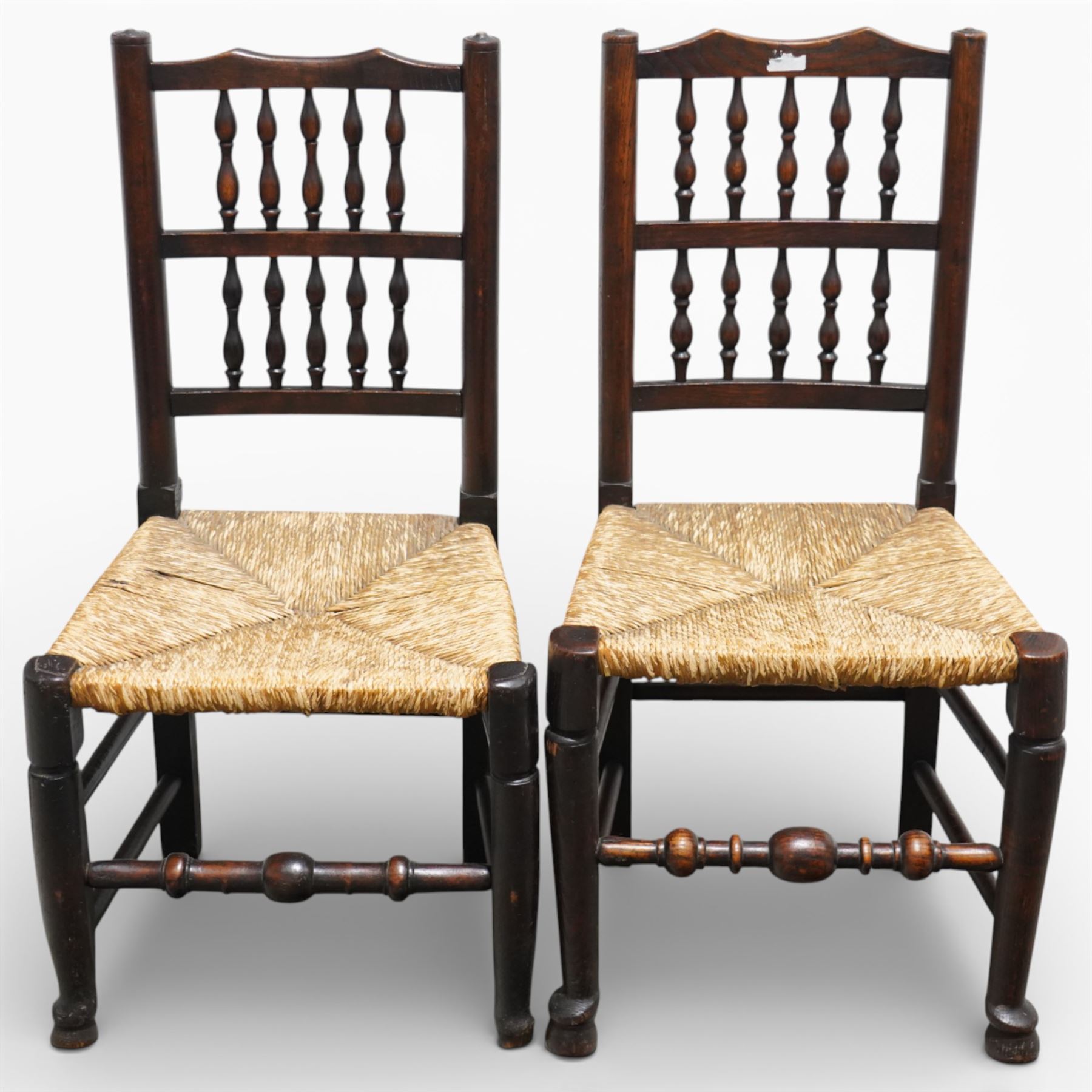 Set of five 19th century elm spindle back chairs, with shaped crest rails above double rows of turned spindles, rush seats, turned legs joined by stretchers supported on turned pad feet
