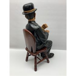 Large painted composite figure of Charlie Chaplin, seated upon wooden chair, H54cm