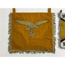 Two replica German Luftwaffe trumpet banners, one heavily silver wire embroidered with Luftwaffe eagle in a wreath, on an amber, white and black rayed background, , with silver wire tasselled border and four leather hanging loops, approx. 50 x 49cm; the other slightly larger heavily gold wire embroidered with the Luftwaffe eagle on a plain amber ground with gold wire tasselled border and two hanging loops (2)