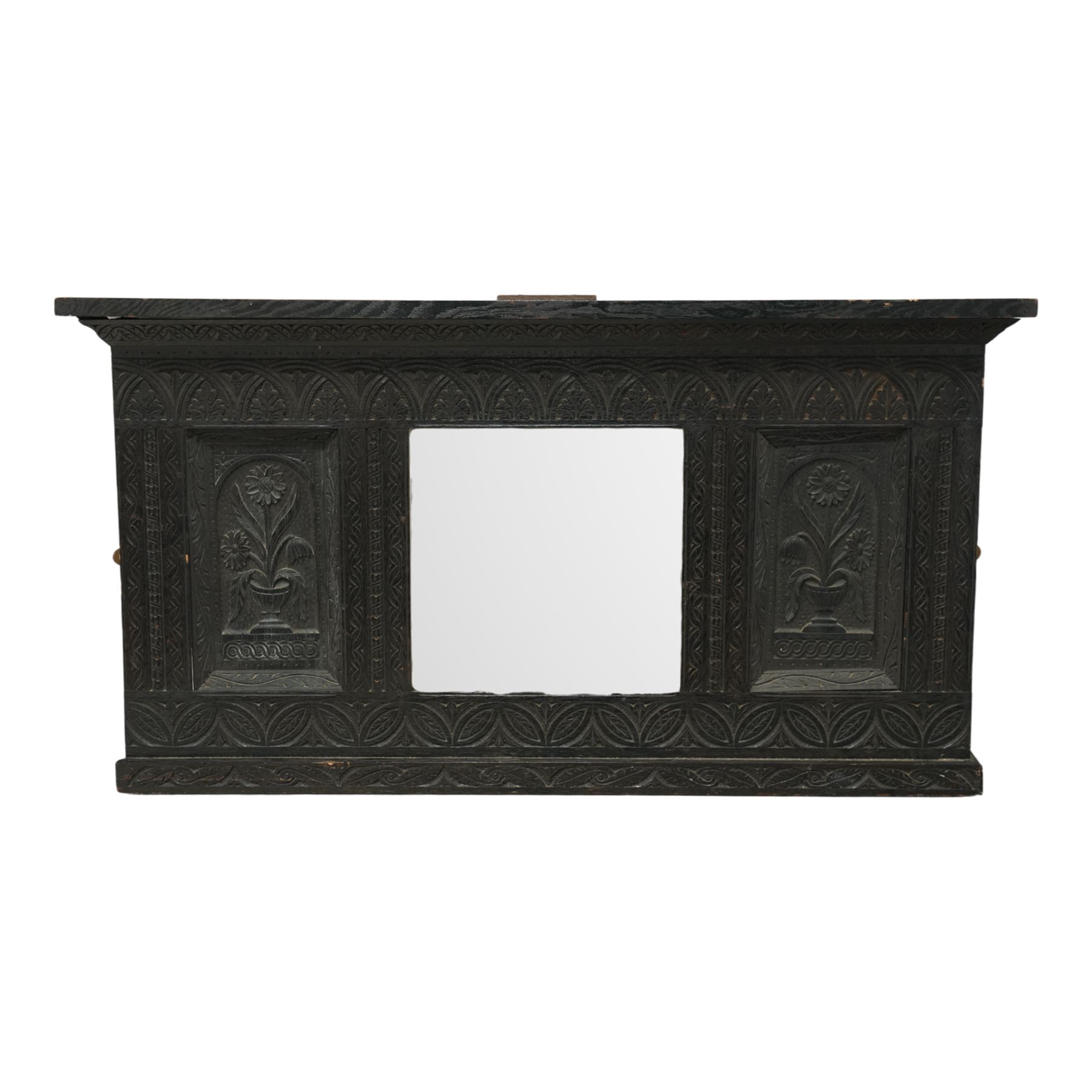Victorian heavily carved oak wall mirror, lunette and foliage carved frieze over central bevelled mirror and flanking panels carved with floral urns, the upright frame decorated with geometric pattern chip carvings, lunette carved lower rail 