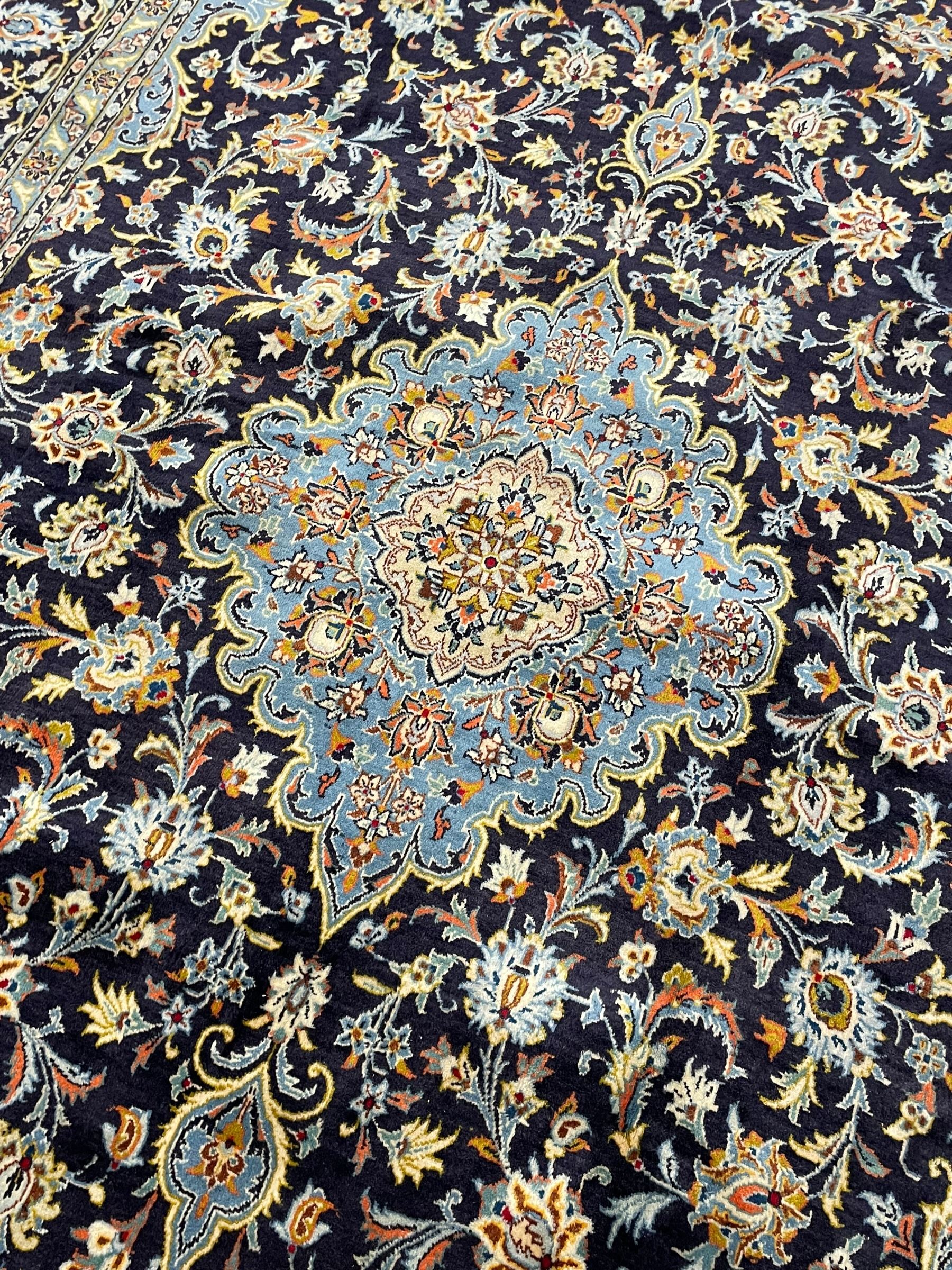 Persian Kashan indigo ground carpet, floral pattern light blue ground central medallion and spandrels, the fielding decorated with interlacing leafy branches and palmettes, the repeating floral pattern border enclosed within guard stripes