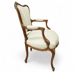 Louis XV design salon suite comprising a pair of walnut and parcel-gilt fauteuil armchairs together with a side chair, the cresting rail surmounted with a carved giltwood floral shell motif with extending foliage, the cartouche shaped backs and sprung seats upholstered in pale blue patterned fabric, over a shaped apron with scallop decoration and foliage carved knees, raised on cabriole supports