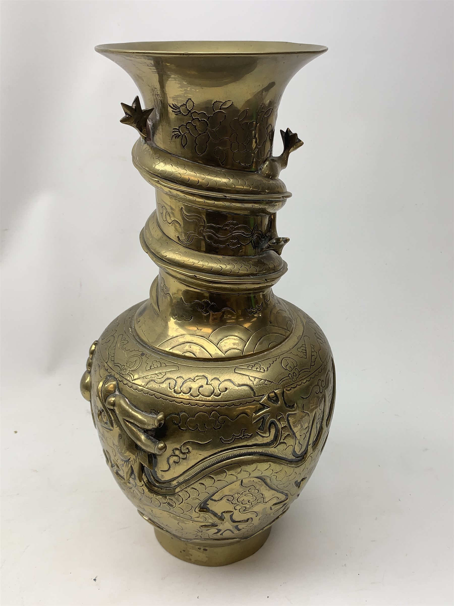 A large Chinese brass vase, of ovoid form with tall neck and flared rim, decorated in relief with dragons chasing a flaming pearl, and further incised with clouds and other detail, the base with relief dragon detail and character mark, H41