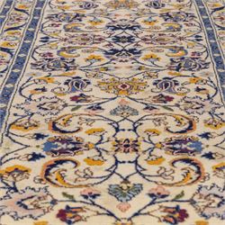 Central Persian Kashan hand-knotted runner, ivory field decorated with an elegant all-over scrolling vine design composed of finely drawn palmettes, floral strays and arabesques in a continuous lattice, principal border on an indigo ground decorated with palmette and vine scroll, flanked by multiple narrow guard stripes, with cotton fringe ends 