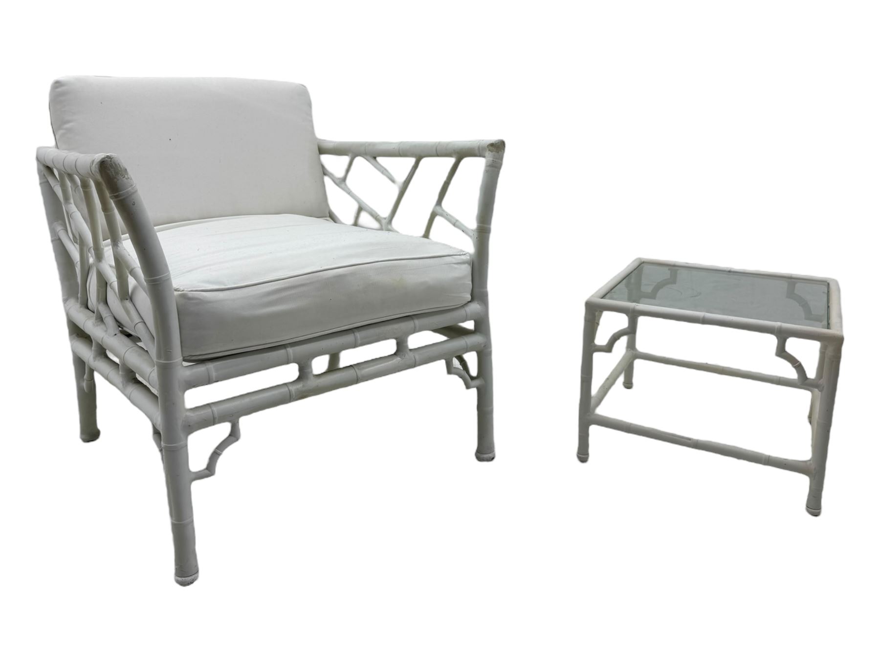 Late 20th century faux bamboo conservatory sofa, white painted frame with geometric openwork back and sides, loose cream cushions, on cylindrical supports (W134cm, D76cm, H80cm); matching armchair (W75cm, D76cm, H80cm); matching coffee table with glass insert (W46cm, D45cm, H36cm)