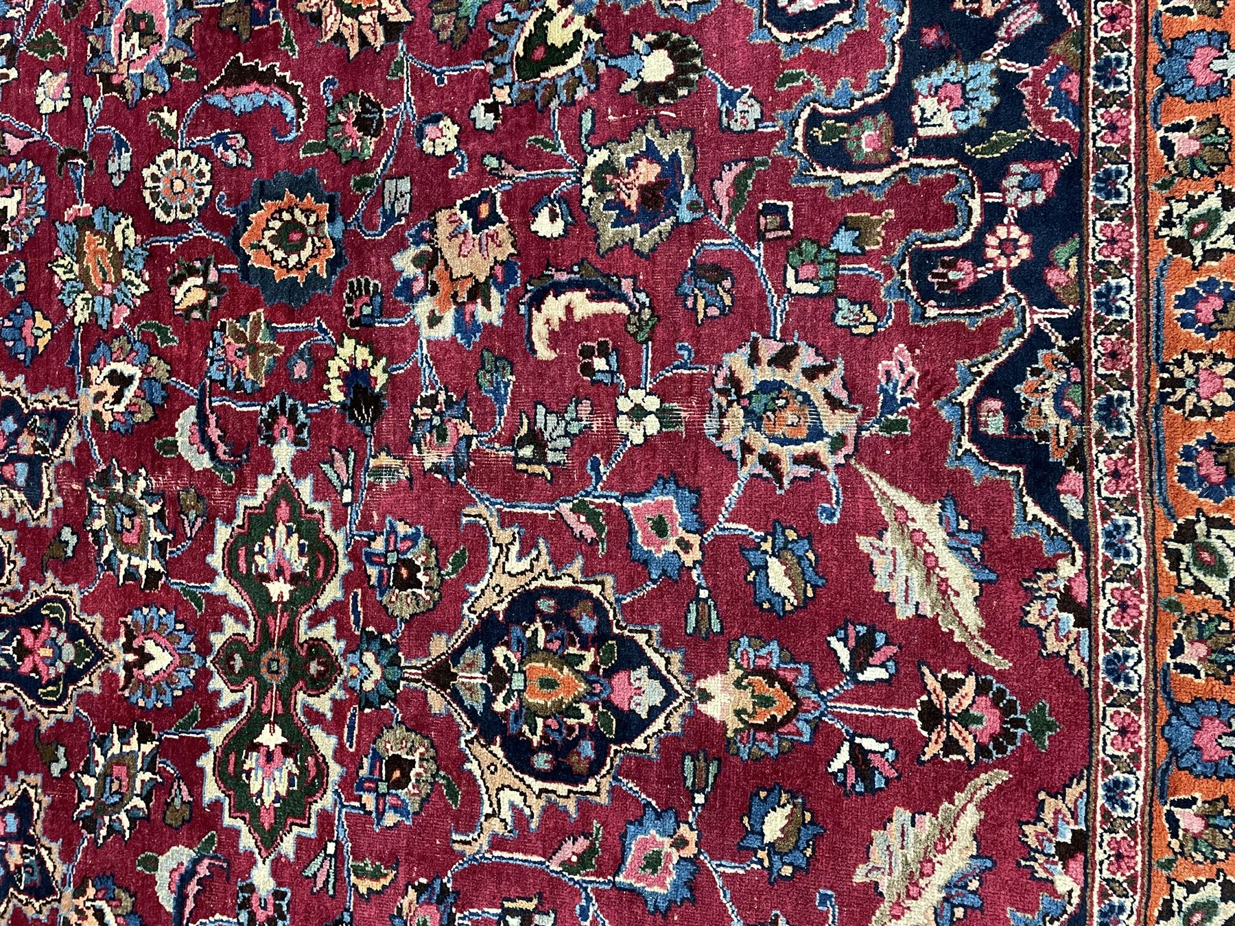 Persian Meshed carpet, plum ground and decorated with stylised flower heads and interlacing foliate, large central stylised medallion with orange detail, the orange mirrored in the five band border decorated with scrolling floral design, signature panel to end 