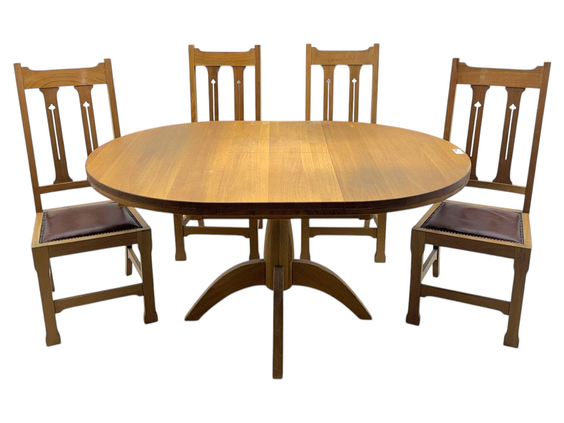 Contemporary light oak round extending dining table with four chairs, table has fold out leaf attached underneath on four out-swept legs, Oak chairs with straight top rail over twin slat back with pierced motifs, brown leather seat with brass studs, square legs joined by plain stretcher 
